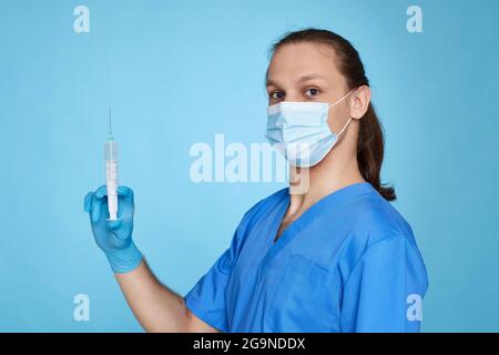 Mann mit einer ärztlichen Uniform, der die Spritze hält Stockfoto
