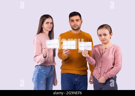 Nahaufnahme von drei Freunden, die in legerer Kleidung vor der Kamera stehen und die Impfstoffzertifizierungen in den Händen halten. Stockfoto