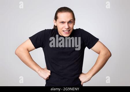 Wütender Mann in schwarzem T-Shirt isoliert auf grauem Hintergrund Stockfoto