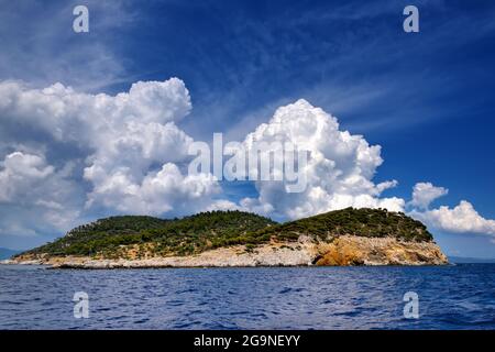 Landschaft mit dem Meer, Insel und schönen Wolken am blauen Himmel. Insel Kelifos, Ägäis, Chalkidiki, Griechenland, Blick vom Meer. Stockfoto