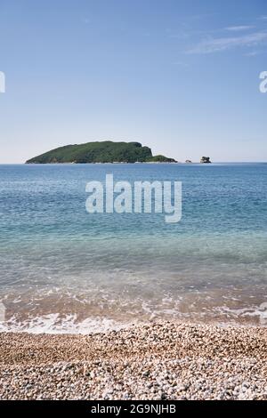 Blick vom Kiesstrand auf die Insel St. Nikolaus. Budva, Montenegro Stockfoto
