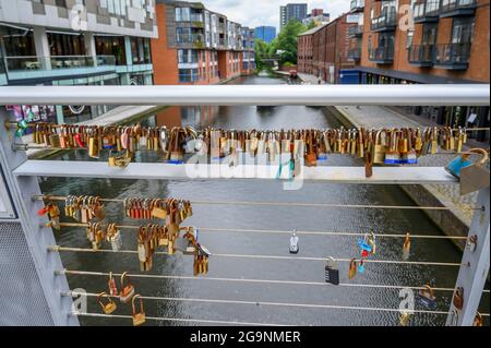 Vorhängeschlösser, die an Geländern auf der Love Lock Bridge über den Birmingham Canal Old Line von The Cube und der Mailbox in Birmingham, England, verschlossen sind. Stockfoto