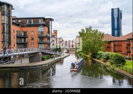 Ein Schmalboot, das auf der Old Line des Birmingham Canal in Richtung Gas Street Basin fährt, mit dem Hyatt Regency Hotel, das sich rechts in Birmingham, England, erhebt. Stockfoto