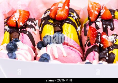 Makronen mit Heidelbeere und Erdbeere. Farbenfrohes und köstliches Dessert mit Schokolade. Nahaufnahme, Draufsicht Stockfoto
