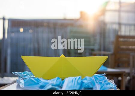 Verschmutzung durch Masken mit einem Papierboot Konzept Kunst. Meer der Masken. Stockfoto