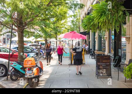 ASHEVILLE, NC, USA-22 JULY 2021: Ein Sommertag auf Page Ave. In der Innenstadt, der Menschen an Straßencafé-Tischen, vorbeispazierende Menschen und zwei bunte Ga zeigt Stockfoto