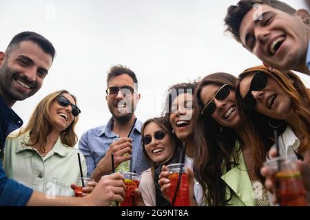 Porträt von jungen Menschen, die draußen Softdrink-Cocktails in Plastikgläsern trinken und die Kamera beobachten. Stockfoto
