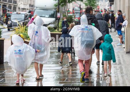 London, Großbritannien. 27. Juli 2021. Touristen tragen Ponchos beim Einkaufen während einer Regendusche in der Regent Street. Laut einer neuen Analyse von Huq Industries, einem Unternehmen für Mobilitätsforschung, führt die britische Covid-App ‘„pingdemic“ zu einer deutlichen Verlangsamung der Menschen, die sich umziehen und Geschäfte besuchen. Im gesamten Vereinigten Königreich ist im Juli die durchschnittliche Kundenfrequenz im Einzelhandel um 2.83 % und die Mobilität um 5.5 % gesunken. Kredit: Stephen Chung / Alamy Live Nachrichten Stockfoto