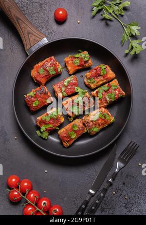 Hausgemachte gefüllte Kohlrollen mit Tomatensauce und frisch gehackter Petersilie in der Pfanne. Flach mit Kohlrollen, Tomaten, Petersilie, Metallgabel legen Stockfoto