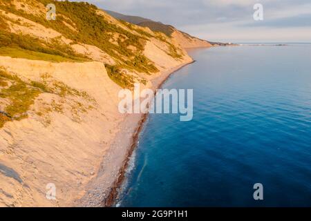 Luftaufnahme der Sommerküste mit Gras und Meer. Küste mit Sonnenuntergangsfarbe Stockfoto
