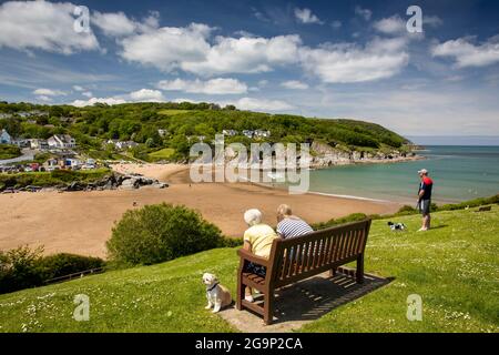 Großbritannien, Wales, Ceredigion, Aberporth, Besucher auf der Bank bei Sonnenschein über dem Strand Stockfoto