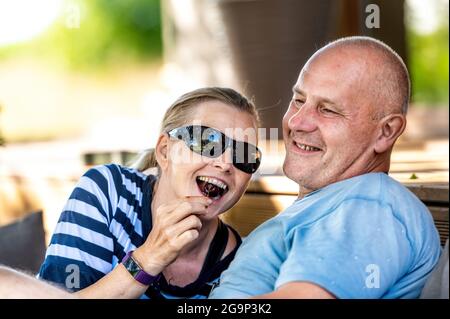 Glückliches Ehepaar, das sich gegenseitig mit Kirschen fütterte, sich im Freien erholte und flirterte Stockfoto