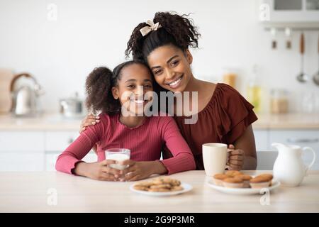 Liebende schwarze Mutter und Tochter genießen frische Kekse Stockfoto