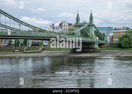 HAMMERSMITH LONDON 27 Juli 2021 . Ruderer passieren die Hammersmith Bridge in West London, die seit April 2019 für Kraftfahrzeuge und alle Nutzer im August 2020 für Radfahrer und Fußgänger wieder geöffnet ist. Hammersmith Bridge ist eine 253 m lange, 134 Jahre alte gusseiserne Hängebrücke, die letztes Jahr wegen Sicherheitskontrollen geschlossen wurde, nachdem Risse entdeckt wurden. Credit amer Ghazzal/Alamy Live News Stockfoto