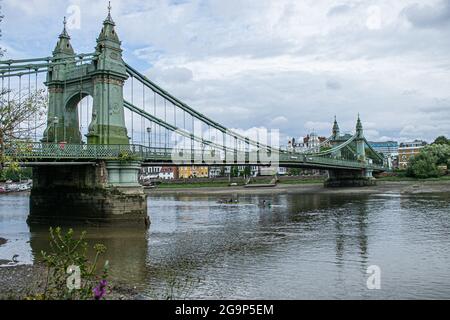 HAMMERSMITH LONDON 27 Juli 2021 . Ruderer passieren die Hammersmith Bridge in West London, die seit April 2019 für Kraftfahrzeuge und alle Nutzer im August 2020 für Radfahrer und Fußgänger wieder geöffnet ist. Hammersmith Bridge ist eine 253 m lange, 134 Jahre alte gusseiserne Hängebrücke, die letztes Jahr wegen Sicherheitskontrollen geschlossen wurde, nachdem Risse entdeckt wurden. Credit amer Ghazzal/Alamy Live News Stockfoto