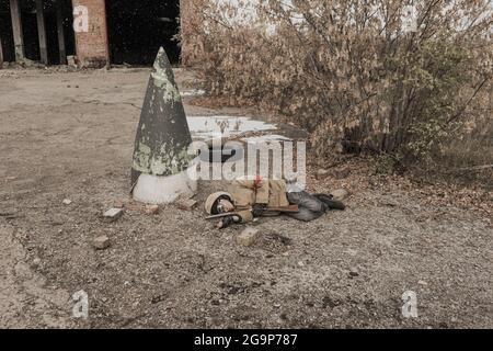 Wandernder Junge. Junge mit einer Waffe. Junge geht zu einem verlassenen Gebäude. Junge steht vor einem Gebäude. Post-Apokalypse. Mann, der zu Fuß in einem Stockfoto