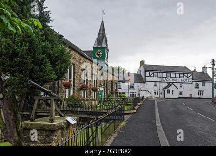 Das Dorf Bellingham in Northumberland, Großbritannien, mit Rathaus und Uhrturm, Black Bull Public House und Gingall-Waffe. Stockfoto