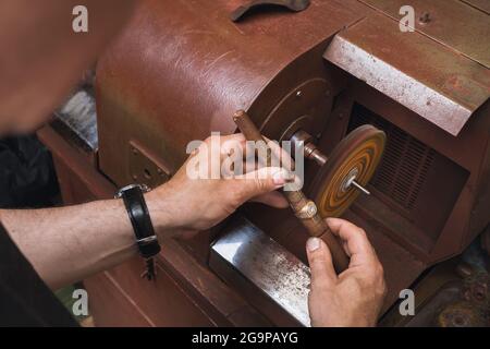 Ein Juwelier poliert einen Goldring an einer Maschine in einer Werkstatt, ein Arbeitsprozess Stockfoto