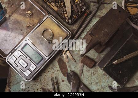 Goldring auf einer Waage, das Arbeitswirr des Juweliers auf dem Tisch, Draufsicht Stockfoto