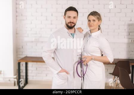 Porträt von zwei selbstbewussten, erfolgreichen Ärzten in Krankenhausuniform, die zusammen posieren Stockfoto