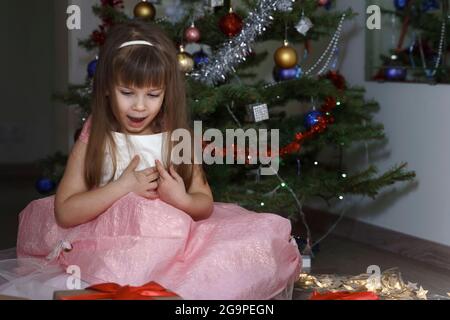 Nettes Baby Mädchen in rosa schönes Kleid von der weihnachtsbaum. Stockfoto