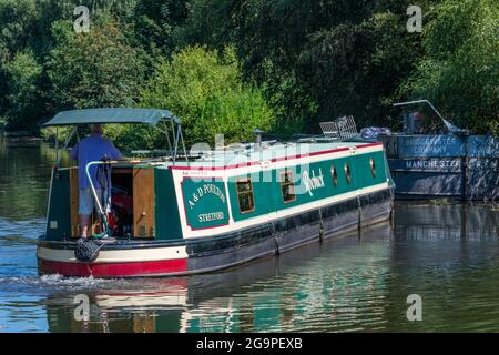 Mann, der am Steuer eines traditionellen Schmalboots oder Barges auf dem bridgewater-Kanal im Verkauf, Greater manchester, großbritannien, steuert Stockfoto