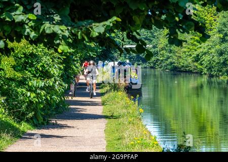 Radfahrer auf dem Abschleppweg des bridgewater Kanals im Großraum manchester mit Kanal und Schmalbooten Kähne auf der Wasserseite neben dem Radweg. Stockfoto