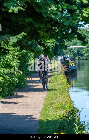 Radfahrer auf dem Abschleppweg des bridgewater Kanals im Großraum manchester mit Kanal und Schmalbooten Kähne auf der Wasserseite neben dem Radweg. Stockfoto