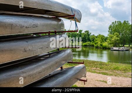 Aluminium-Kanus auf einem Anhänger mit einer Strandfront und offenem Wasser im Hintergrund gestapelt Stockfoto