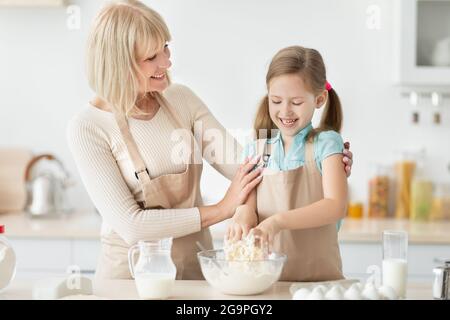 Glückliche ältere Frau und ihre Enkelin, die Teig zubereitet Stockfoto