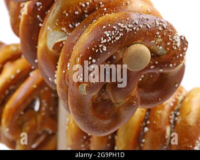 Frisch gebackene bayerische Brezel auf traditionellem Holzständer isoliert auf weißem Hintergrund, Nahaufnahme Stockfoto