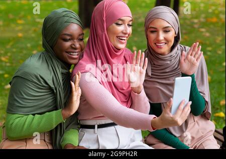 Muslimische Damen Machen Videoanruf Mit Telefon Winkende Hände Im Freien Stockfoto