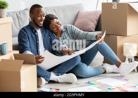 Schwarze Ehepartner Planen Renovierung, Überprüfung Blueprints Und Farbpalette Stockfoto