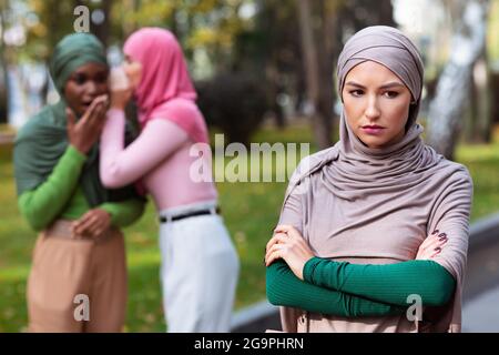 Islamische Damen Flüstern Hinter Ihrem Unglücklichen Freund Im Freien Stockfoto
