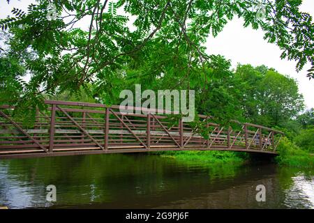 Fußgängerbrücke aus Stahl mit Holzsteg, der einen schmalen Abschnitt des Delaware- und Raritan-Kanals im Colonial Park -11 überquert Stockfoto