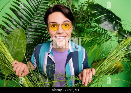 Foto von cool Brunet jungen Kerl im Dschungel tragen Brille Hemd isoliert auf grünem Hintergrund Stockfoto