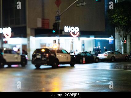 Verschwommene Nachtaufnahme eines Polizeiwagens, der in der Nähe des IHOP-Restaurants, Ecke 8th Street & Flower Street, Downtown Los Angeles, California, USA, geparkt ist Stockfoto