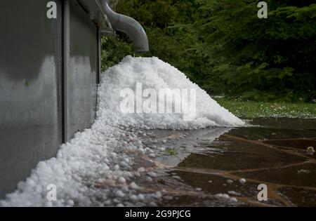 Haufen Hagel Kugeln unter Regenrinne in überfluteten Garten nach schweren Gewitter Stockfoto