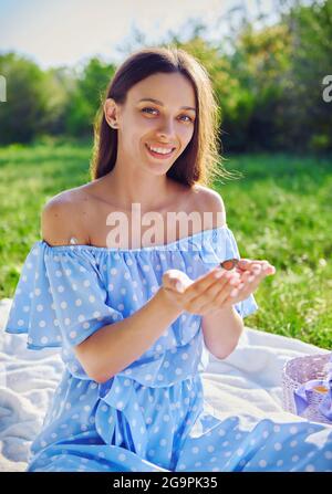 Picknick-Szene: Glücklich lächelndes Mädchen hält Schmetterling in den Händen. Porträt einer fröhlichen jungen Frau im Garten Stockfoto