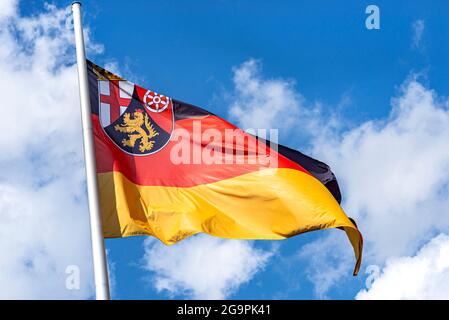 Deutsche Flagge auf einem im Wind winkenden Pfahl mit dem Wappen des Landes Rheinland-Pfalz. Stockfoto