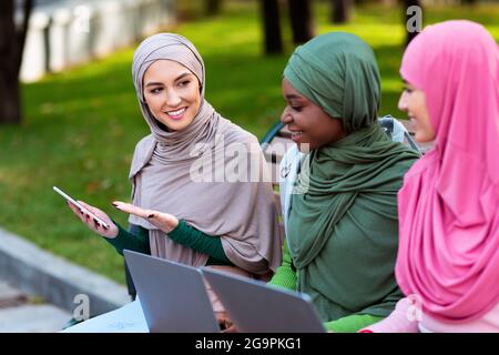 Muslimische Frau Zeigt Freunden Smartphone Und Empfiehlt Anwendung Im Freien Stockfoto