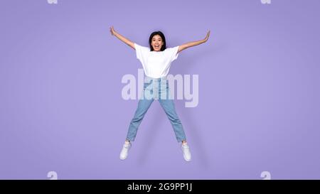 Sorglose Aisan Young Lady Springen Spreadeagle Über Purple Studio Hintergrund Stockfoto