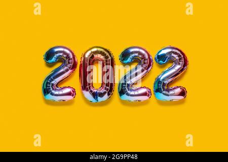 Frohes neues Jahr 2022 Feier. Mehrfarbige Folienballons Zahl 2022 auf gelbem Hintergrund. Flach liegend. Stockfoto