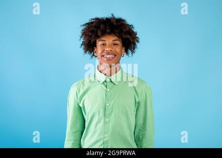 Lässiges Teenagermodell. Porträt eines lächelnden afroamerikanischen Mannes, der die Kamera auf blauem Hintergrund anschaut Stockfoto