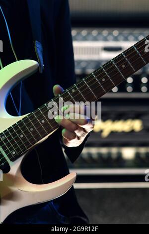Finger des Musikers drücken Saiten auf die E-Gitarre. Nahaufnahme Hand des Musikers, der Gitarre spielt. Rockmusik-Konzept. Repetition Rock-Musik des E-Gitarristen. Probenbasis Stockfoto