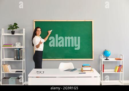 Der Lehrer schreibt eine Lektion auf der Tafel in der Schule. Stockfoto