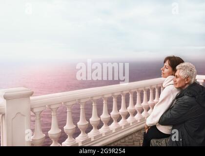 Mann und Frau auf einer Terrasse über dem Meer umarmen. Stockfoto