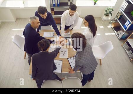 Draufsicht auf eine positive Gruppe von Kollegen, die sich als Symbol für Zusammenarbeit und Unterstützung die Hände halten. Stockfoto