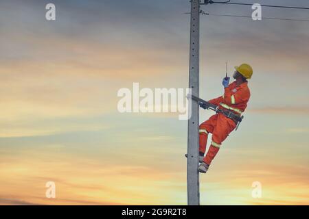 Installation von Schalt- und Anschlussleitungen an einem Mast. Ein Elektriker arbeitet an einer Stange.Linemen. Stockfoto