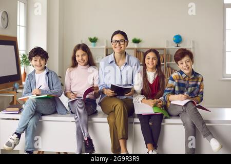 Porträt einer Lehrerin und ihrer Grundschüler mit Notizbüchern in den Händen. Stockfoto